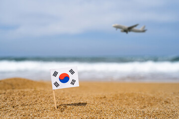 Flag of South Korea in the form of a toothpick in the sand of beach opposite sea wave with landing...