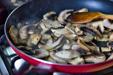 Top view of Fresh cut mushroom are being cooked in fry pan with steam coming out showing home cooking vegan concept