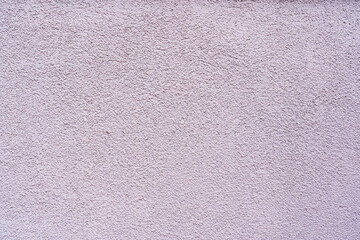 Fragment of the new wall of a stone building. The plaster has a fine texture and a light purple color. Background.