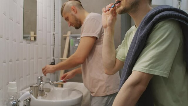 Tilt up shot of young men brushing their teeth in bathroom before going to bed
