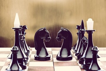 Black chess pieces facing each other on a vintage chessboard. Rivalry concept,
