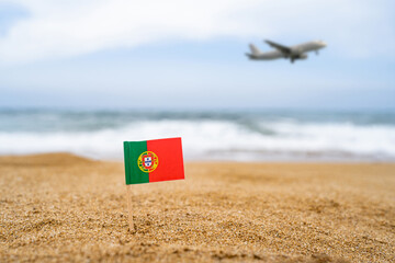 Flag of Portugal in the form of a toothpick in the sand of beach opposite sea wave with landing...