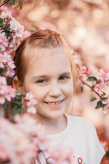 Fototapeta premium Pretty teen girl with nice smile looking at camera. Apple tree blossom.