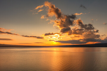 Dramatic golden sunset sky background. yellow sun sets behind the lake. Beautiful sunrise on the lake.