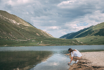 Fototapeta na wymiar Child throwing stones on lake braies in south tyrol, italy. rear view
