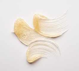 Transparent smear and texture of golden cosmetic gel on a white background.