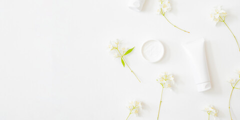 Flat lay composition with cosmetics and jasmine flowers on a light background