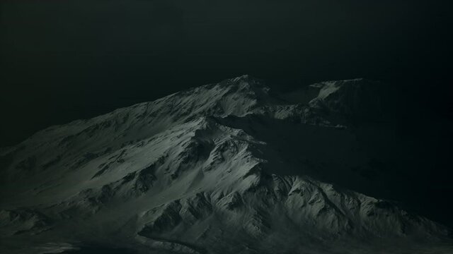 Dramatic dark rocky mountain with patches of snow in storm
