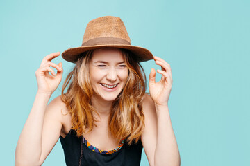 Happy young blonde girl smiling with a straw hat on a blue background. Summer concept. Copy space