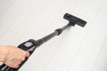 Cleaning the house. The woman is vacuuming the floor.