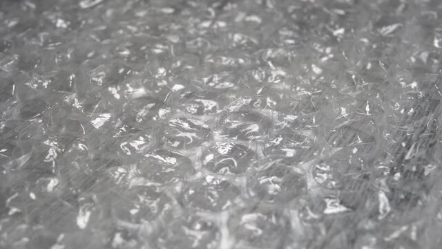Bubble wrap glitters and rotates. Macro shot. Recycled polyethylene material for fragile parcels. Abstract detailed light background. Selective focus