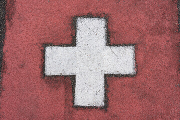 Swiss flag painted on asphalt in the country's colors. Alphast texture and paint colors.