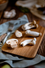 Dark photography of mushrooms, asparagus, bread, garlic and plums on a table of old wood. Vegetables recipe of for autumn or winter. Moody picture of seasonal cultivated fungus on a wooden table.