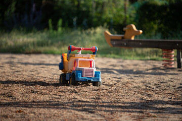 toy truck in sand on a playground, seesaw in the background