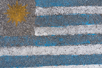 Fototapeta na wymiar Uruguay flag painted on the asphalt in the country's colors. Alphast texture and paint colors.