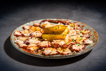 Dark food photography of sliced octopus beautiful decorated. Moody image of modern version of a modern cuisine of a typical spanish tapas meal.