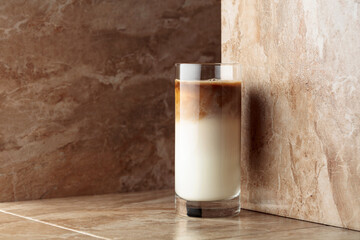 Milk coffee cocktail on a beige ceramic table.