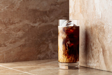 Iced coffee with cream on a beige ceramic table.