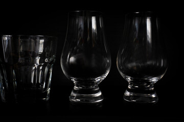 Two empty whisky glasses and a rocks glass on a dark background