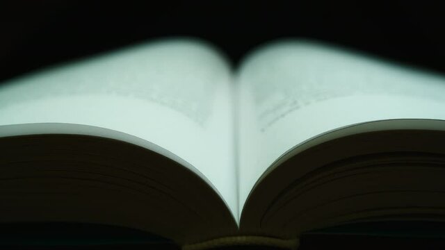 The pages of an open book are flipped over against a dark background. Close-up shooting