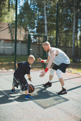 Professional basketball player instructor train little kid boy, holding phone in hand, taking video for social networks