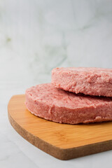 raw burger meat with herbs over a wood table, green background