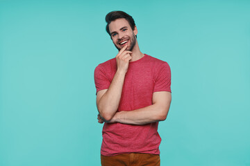 Handsome young smiling man in casual clothing looking at camera and holding hand on chin