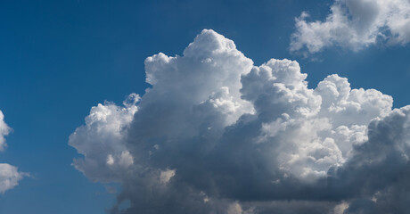 Naklejka na ściany i meble Beautiful cumulus clouds against the blue sky.. Panoramic shot of a cloud cluster. Wide format.