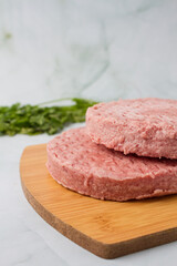 raw burger meat with herbs over a wood table, green background