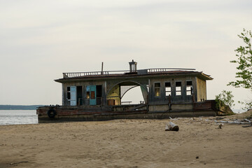 An old abandoned landing stage on an empty beach. Broken wooden building on the shore.
