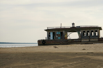 An old abandoned landing stage on an empty beach. Broken wooden building on the shore.