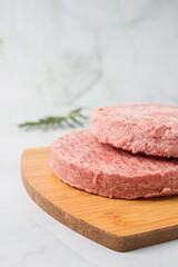raw burger meat with herbs over a wood table, green background