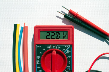 Multimeter with text on display 220 V and heat shrink insulation on white background