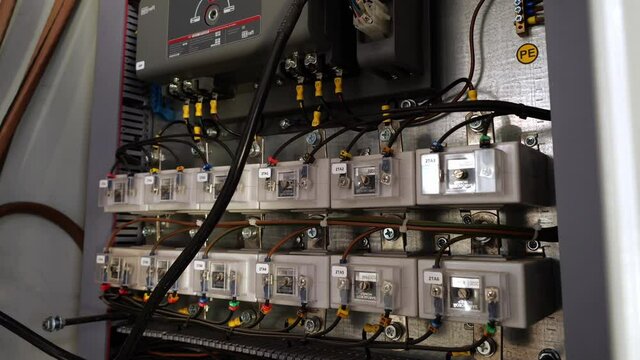 Rows of contemporary circuit breakers with locks on switchboard with connecting cables in production plant workshop