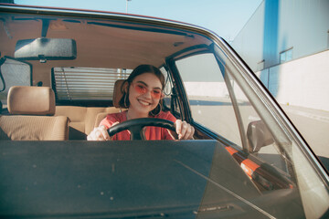 Girl wearing sunglasses sitting behind the wheel in the driver's seat