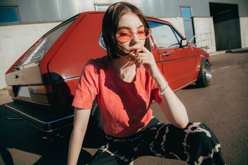 Girl posing to the camera in front of her car around the urban views