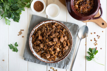 A hearty meal for the family: lentils with meat and vegetables on a white plate on a white table.