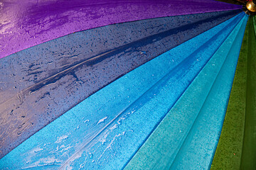 Wet waterproof textile surface of blue gradient colored umbrella under drizzle rain. Water drops...