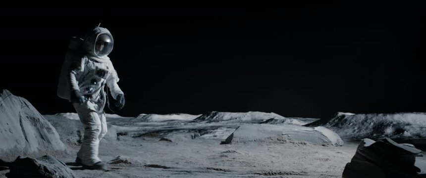 Male astronaut performing moonwalk dance move on a Moon surface. Shot with 2x anamorphic lens