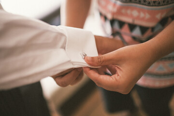 Girl helping boy to button his shirt on his wedding day