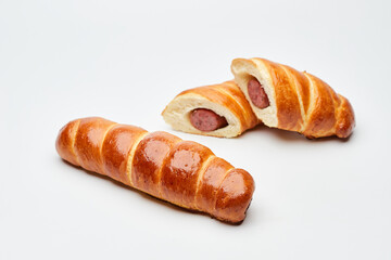 Rolled hot dog sausages in the dough baked in puff pastry isolated on white background