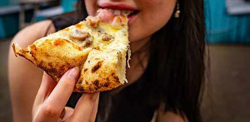 woman Hand takes a slice of meat Pizza. young woman eating pizza outdoor in street