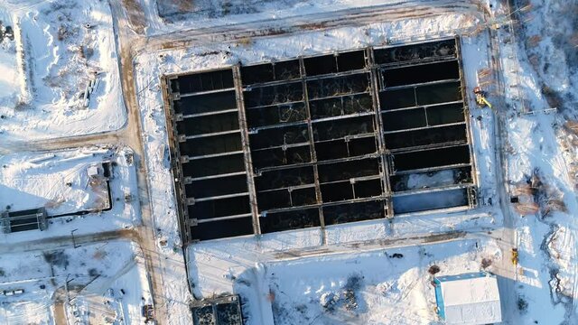 Set of basins with dirty processed water and bridges at modern purification station in early winter morning aerial view