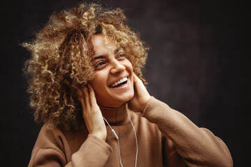 Girl with a smile on her face holding hands on her ears and enjoying music.