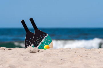 Rackets and ball on the sandy beach. Summer sport concept
