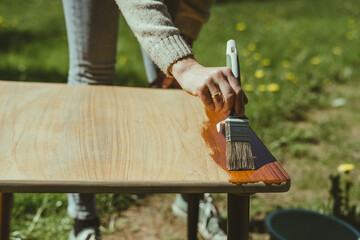 Selective focus of a painter hand applying polyurethane on a wooden table
