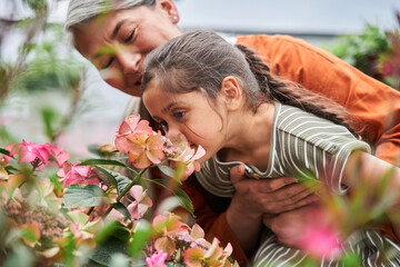 Girl smells a flowers while enjoying of her childhood at the greenhouse