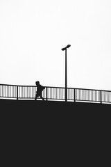 silhouette of a person walking on a bridge