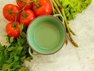 empty saucepan, asparagus, tomato, herbs on concrete background
