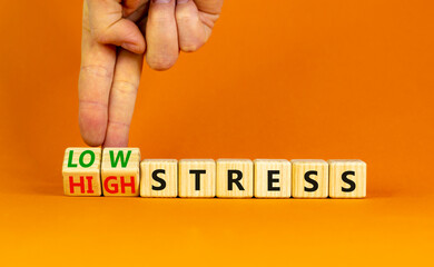 Low or high stress level symbol. Businessman turns wooden cubes and changes words high stress to low stress. Beautiful orange background. Low or high stress level concept. Copy space.